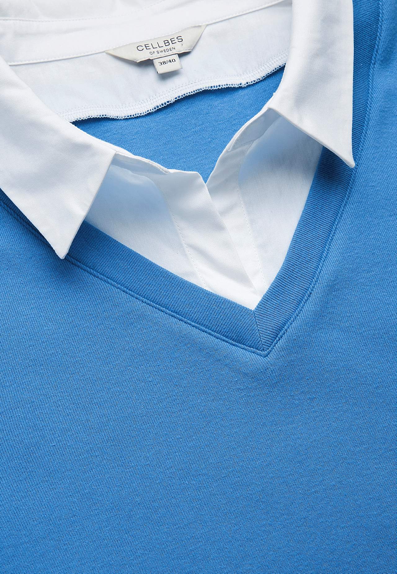 Trikootoppi kiinniommellulla paidan kauluksella